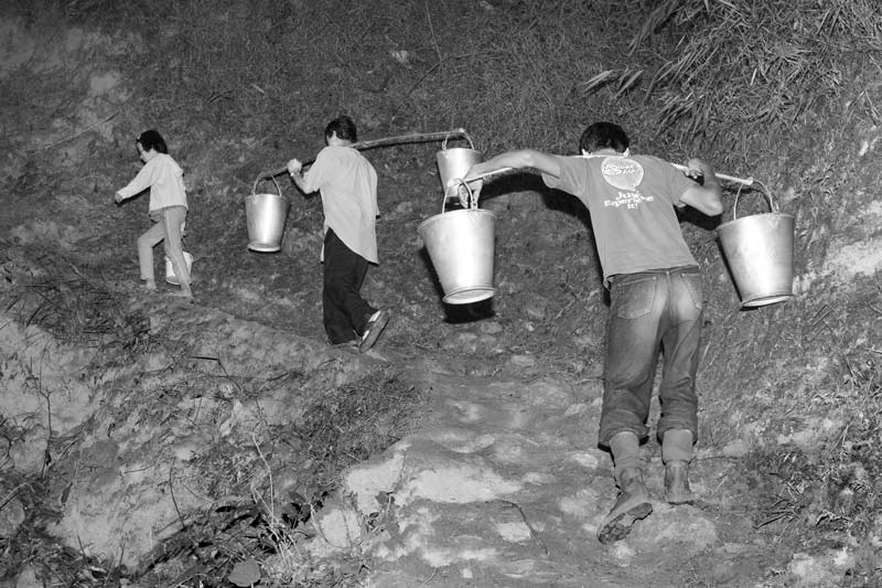 Rural Drinking Water Challenges - men hauling drinking water buckets at dawn up to their village located on a hilltop in district Zunheboto, Nagaland